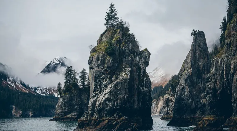 Fog-shrouded sea stacks and calm water in Resurrection Bay near Seward, Alaska